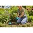 Person pflanzt Blumen mit Handschuhen und Schaufel ein