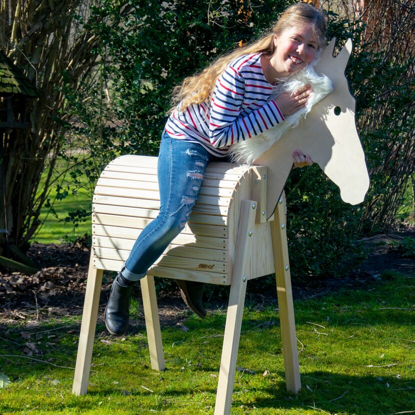 Kind reitet auf einem Holzpferd.