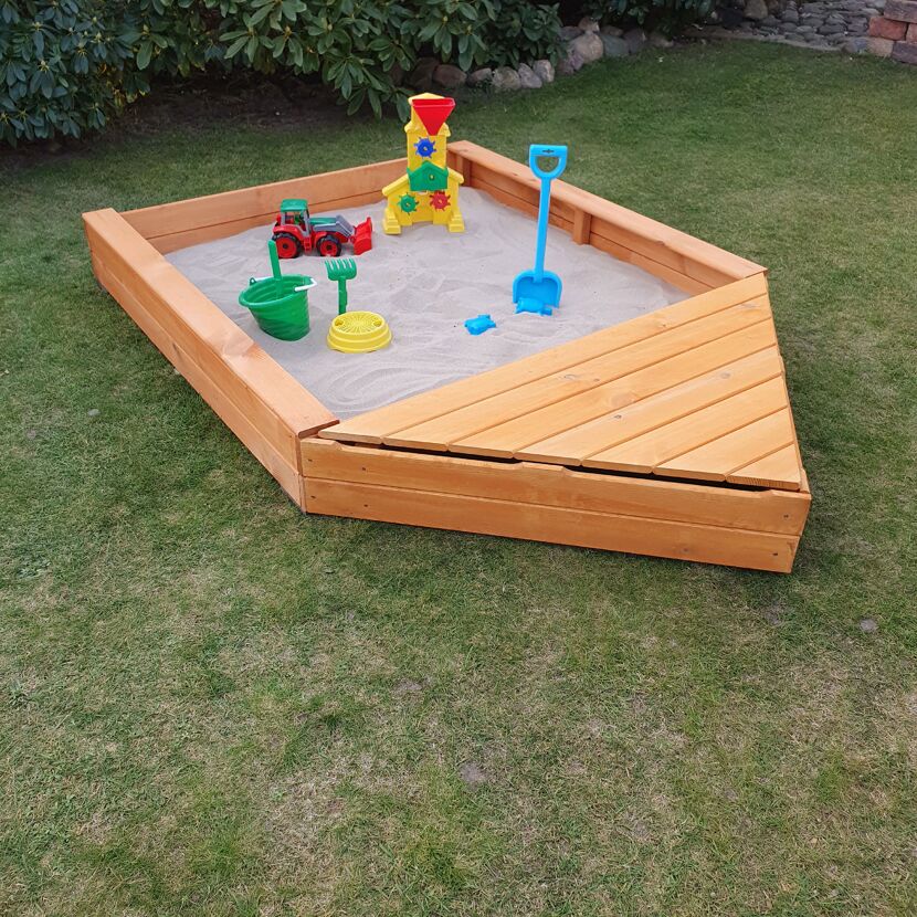 Hölzerner Sandkasten in Bootsform mit Spielzeug