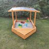 Hölzerner Sandkasten mit Dach und Sandspielzeug