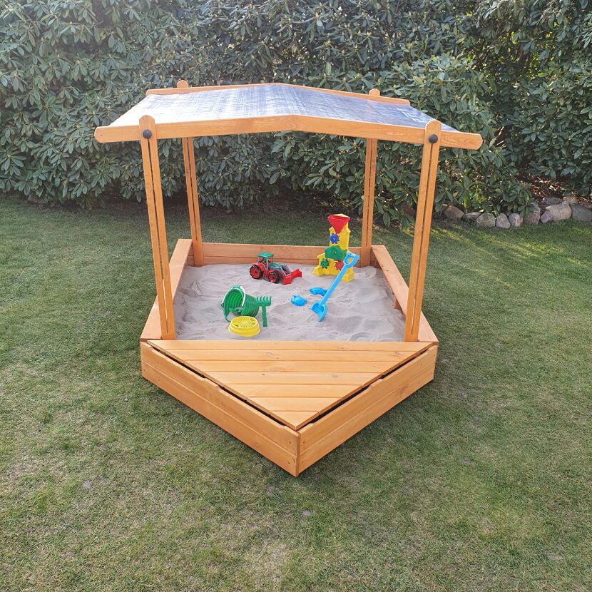 Hölzerner Sandkasten mit Dach und Sandspielzeug