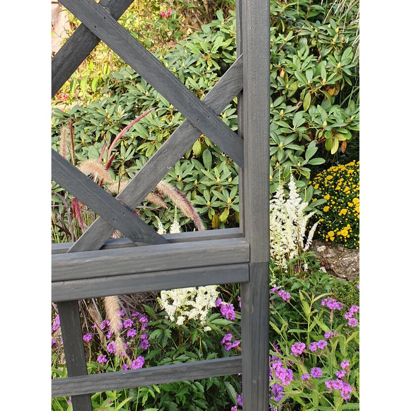 Schwarzes Holzgitter vor Blumen
