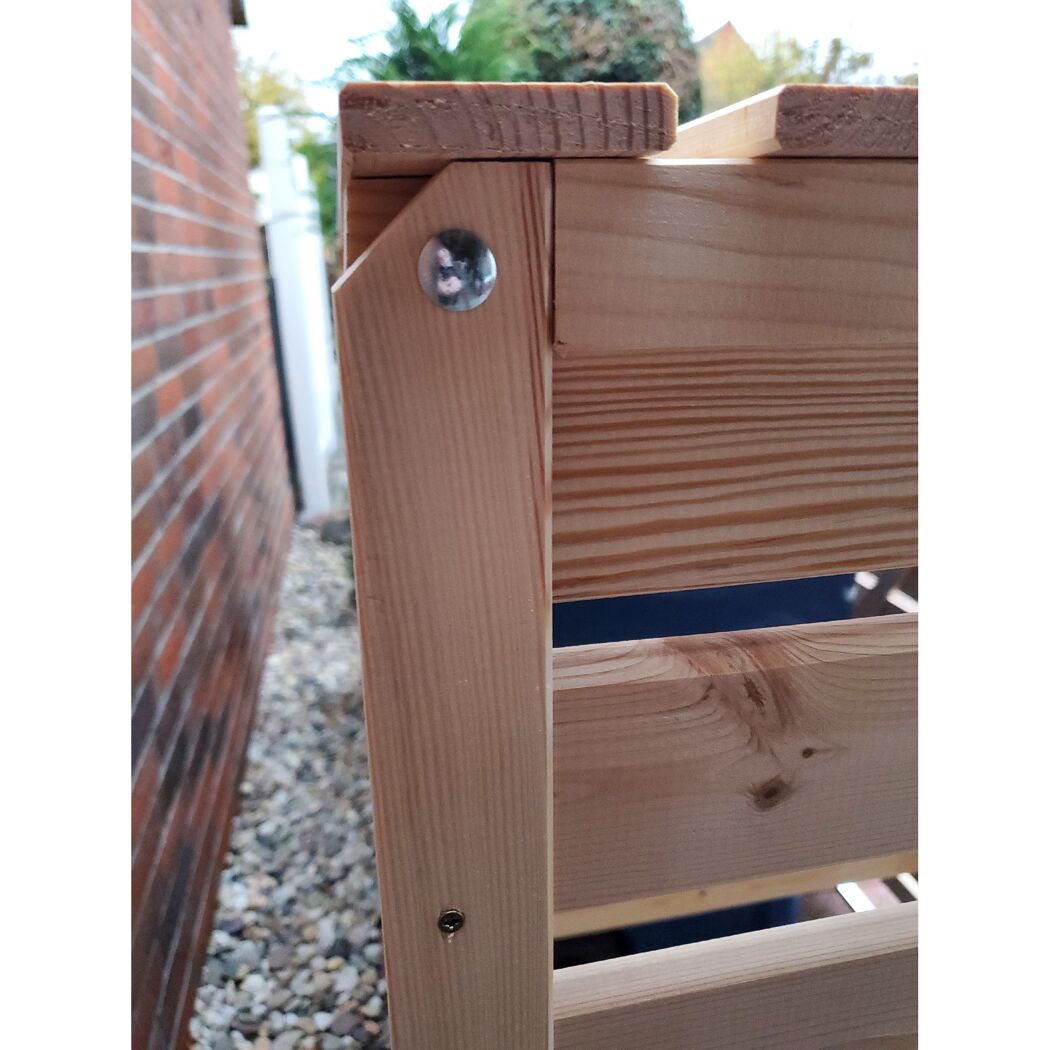 Ecke einer Mülltonnenbox aus Holz mit Schraube