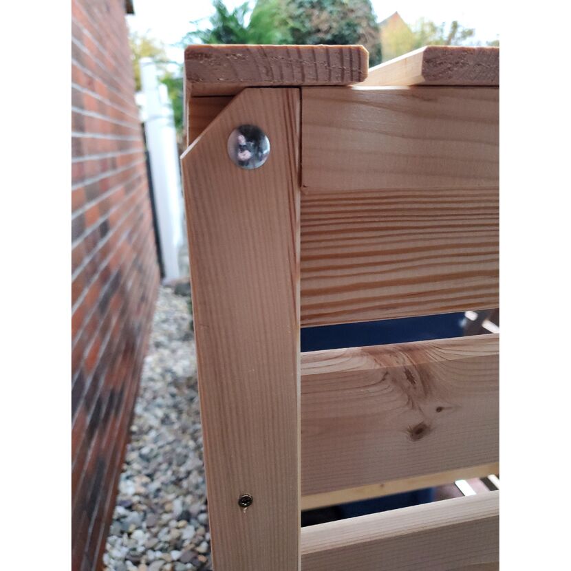 Ecke einer Mülltonnenbox aus Holz mit Schraube