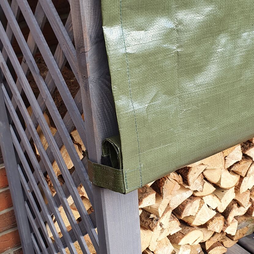 Grauer Holzstapel mit grüner Plane
