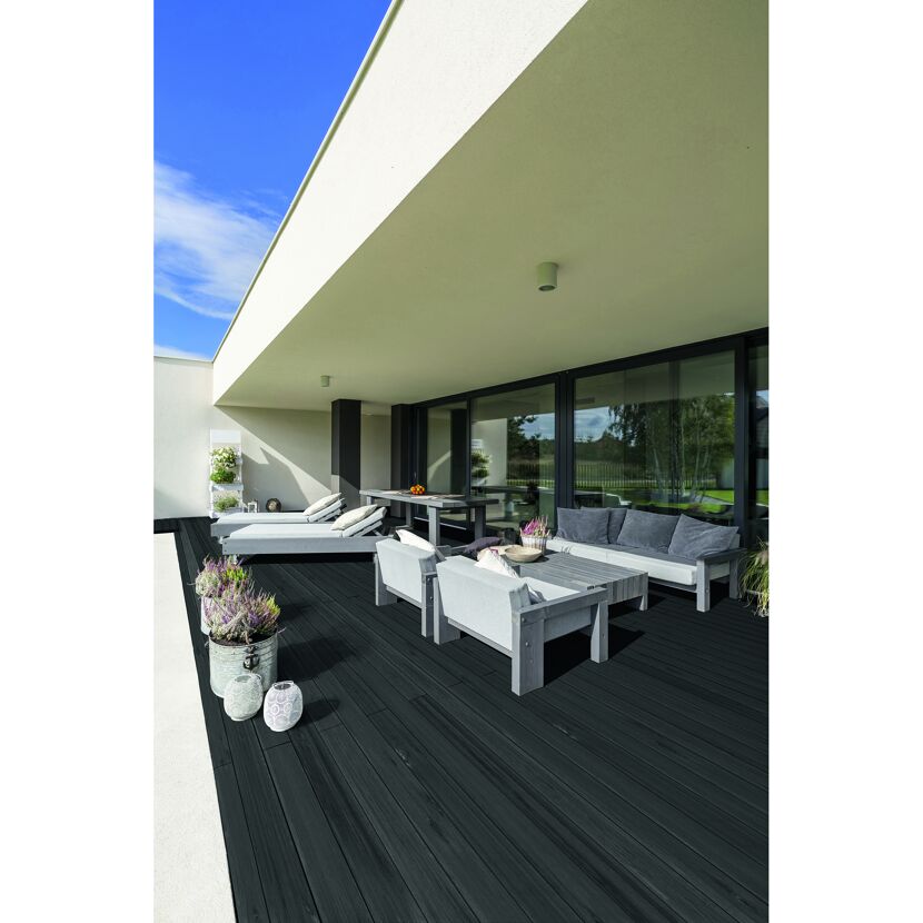 Schwarze Holzterrasse mit Gartenmöbeln, Töpfen und Laternen.