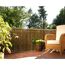 Balkon mit Weidenmatte, Korbstuhl und Blumen