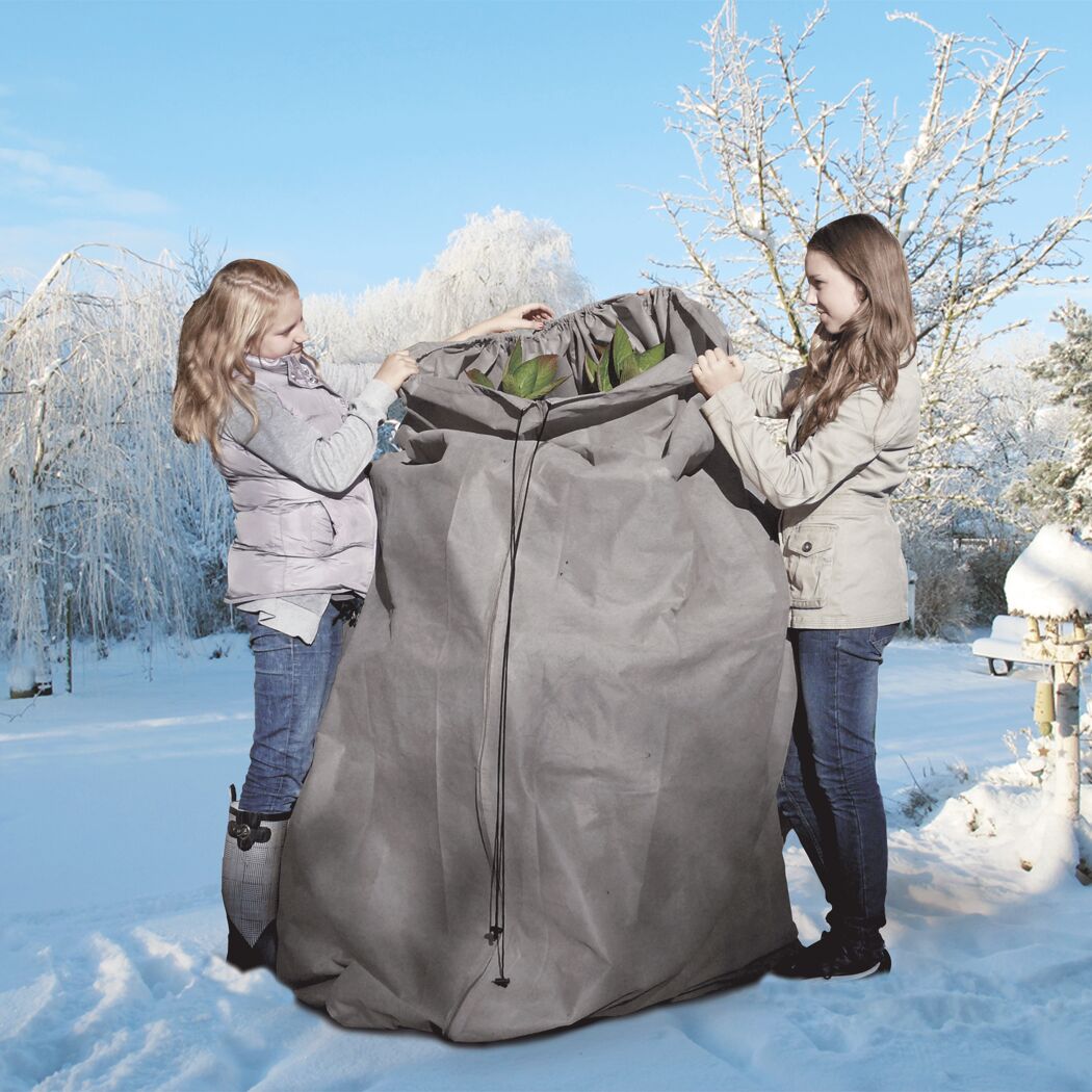 Zwei Kinder halten einen Winterschutz für Pflanzen.