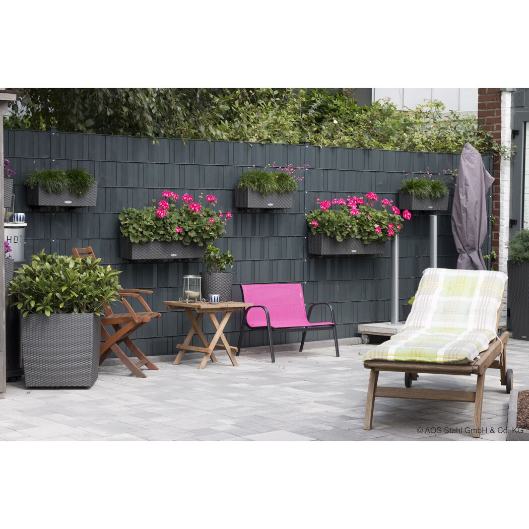 Blumenkästen und Gartenmöbel vor einem Sichtschutzzaun