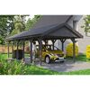 Person parkt gelbes Auto unter einem grauen Carport.