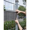 Person bringt Sichtschutz an einem Zaun an