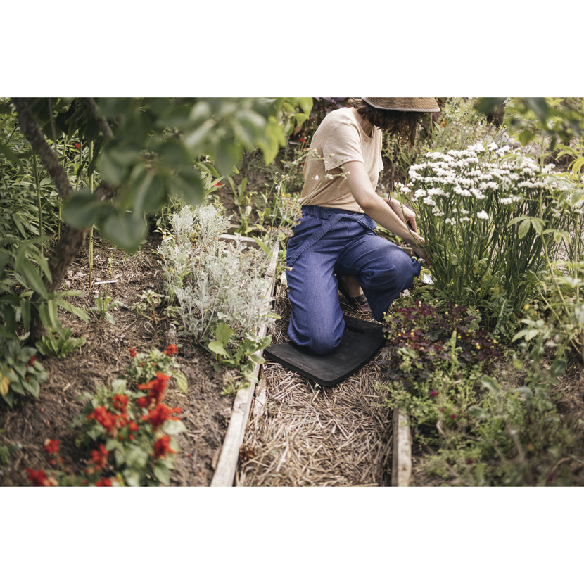 Person schneidet mit Gartenschere Blumen auf einem Kniekissen.