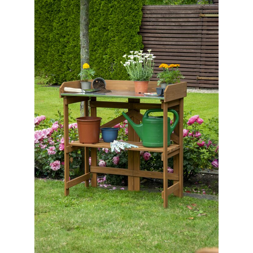 Klappbarer Pflanztisch aus Holz mit Blumen und Gießkanne.
