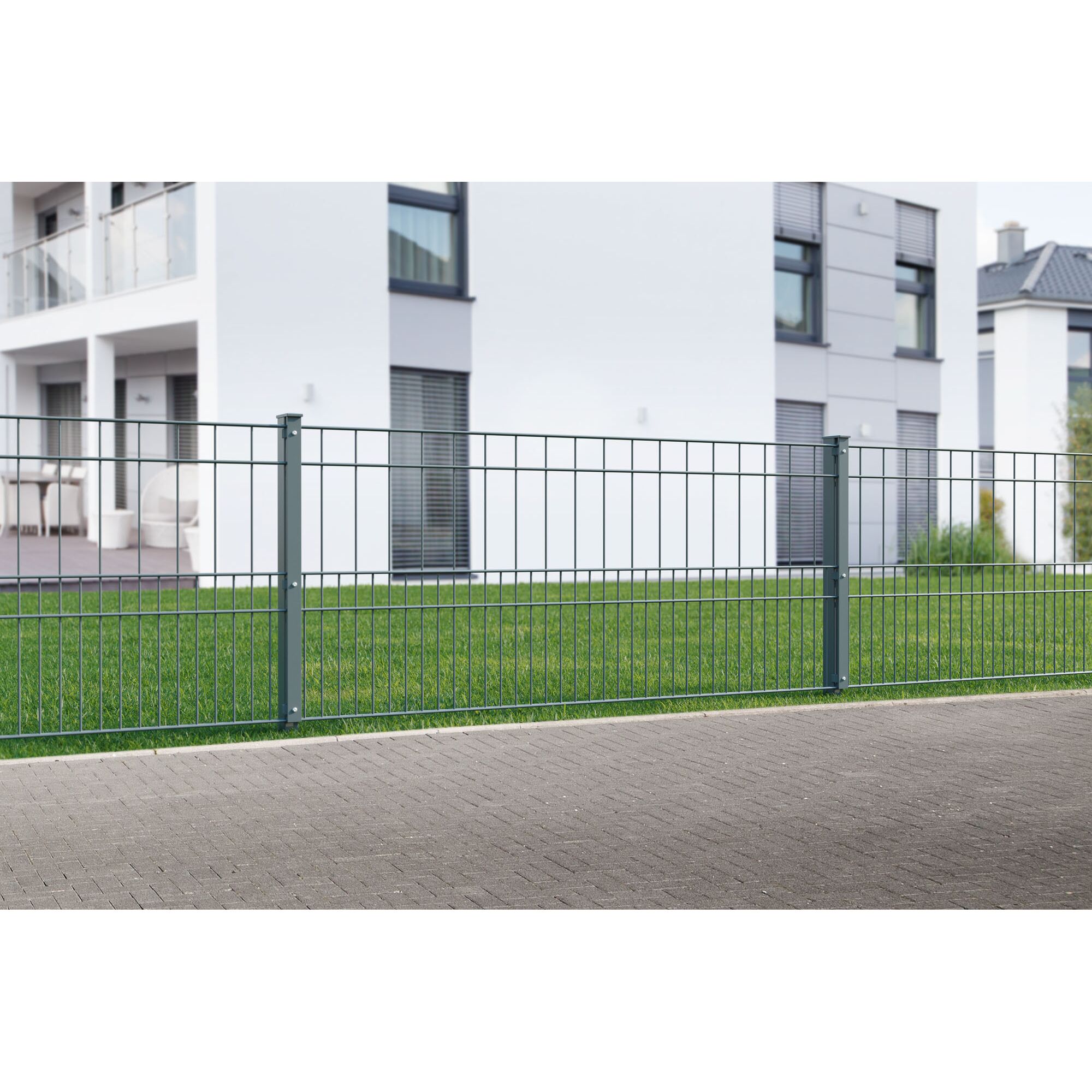 Grüner Metallzaun vor einem Haus