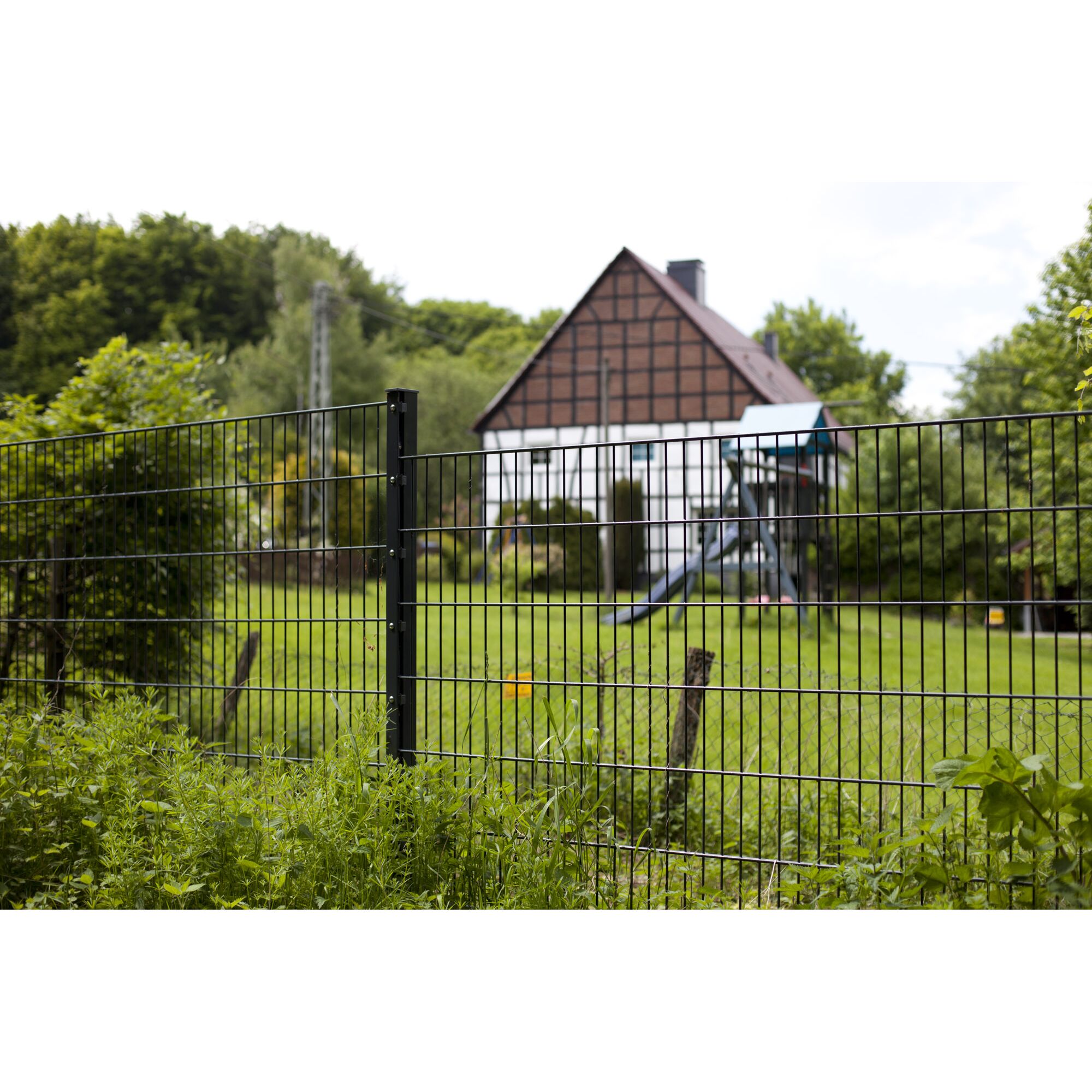Schwarzer Zaun vor einem Haus mit Spielplatz