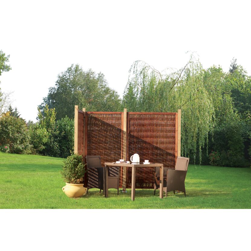 Tisch und Stühle hinter Weidenwand im Garten