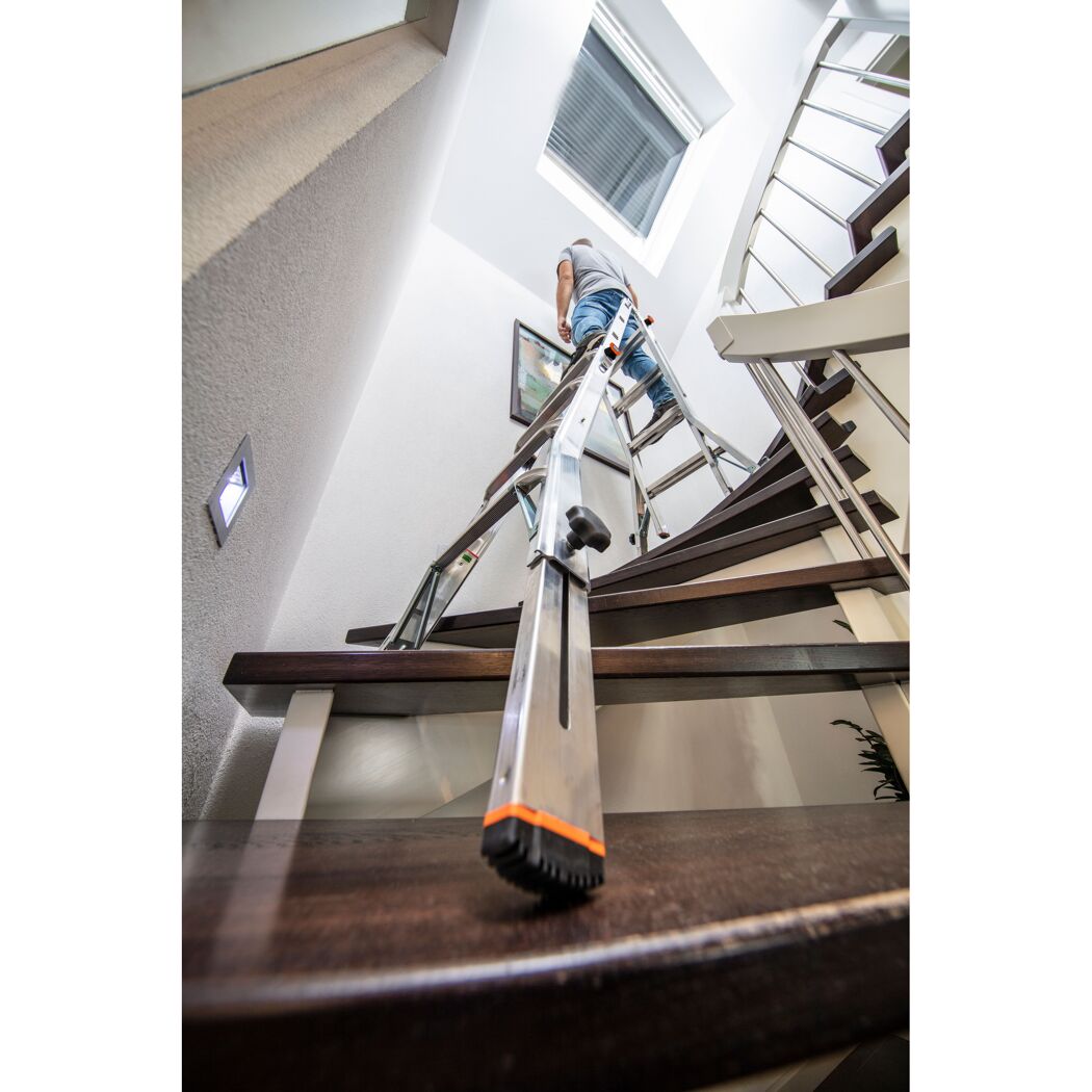 Person auf Teleskopleiter an Wendeltreppe