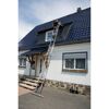 Person arbeitet mit Leiter am Hausdach.