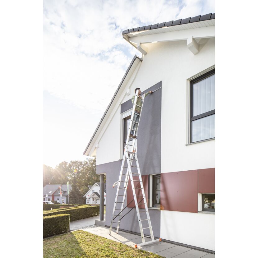 Person auf Leiter an Hausfassade
