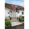 Person auf Leiter mit Eimer vor Haus