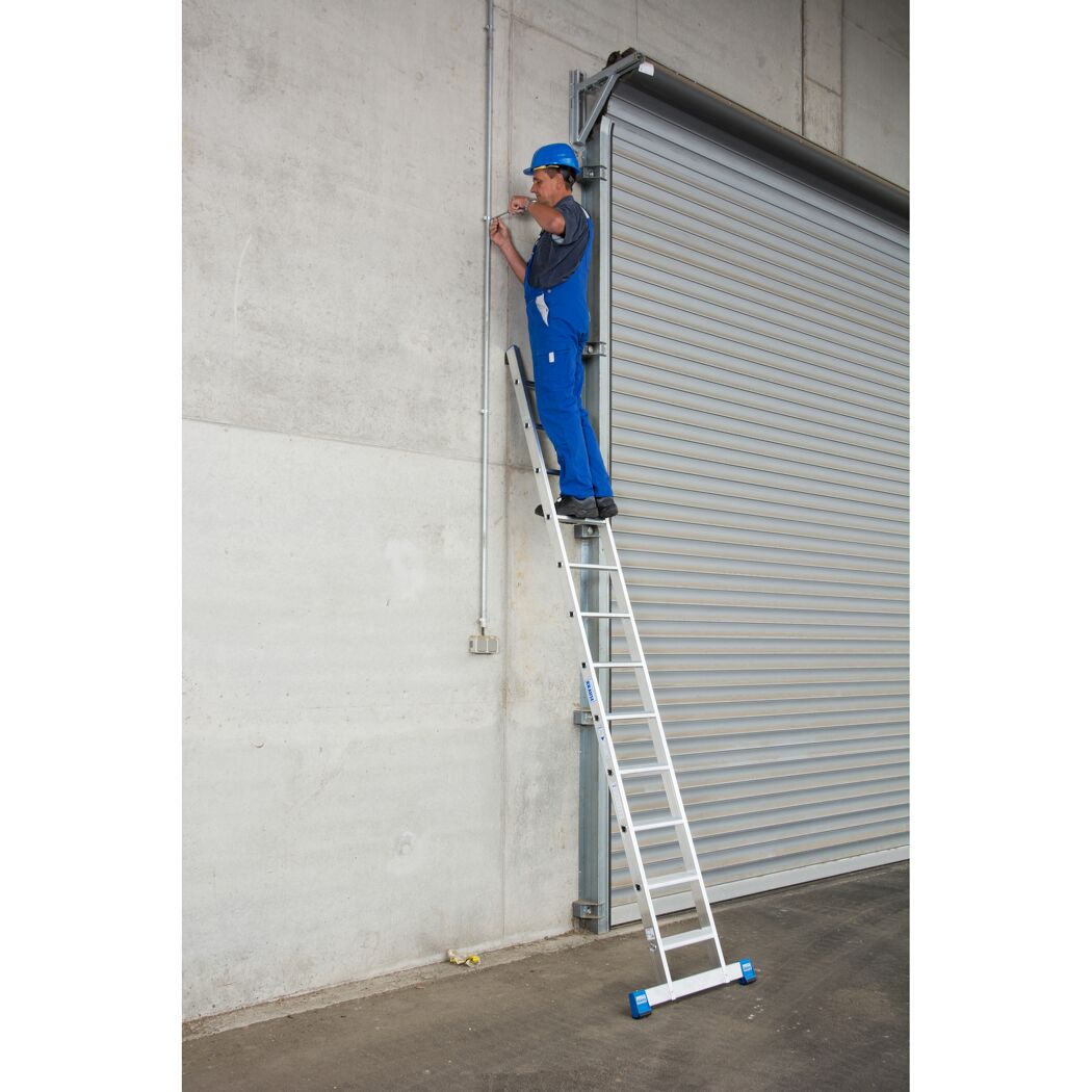 Person auf Anlegeleiter mit Werkzeug an Wand