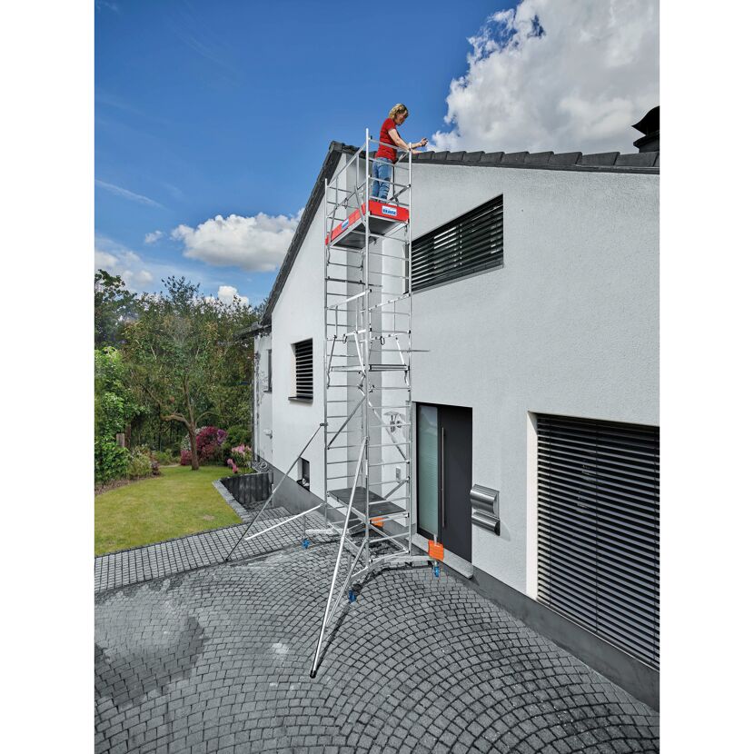 Person auf einem Gerüst neben einem Haus