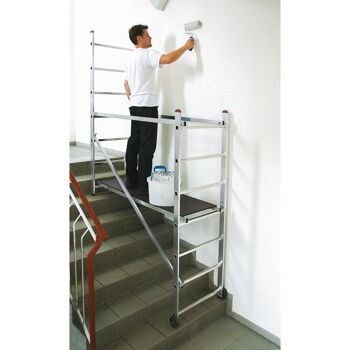Person streicht Wand mit Farbrolle auf einem Kleingerüst.