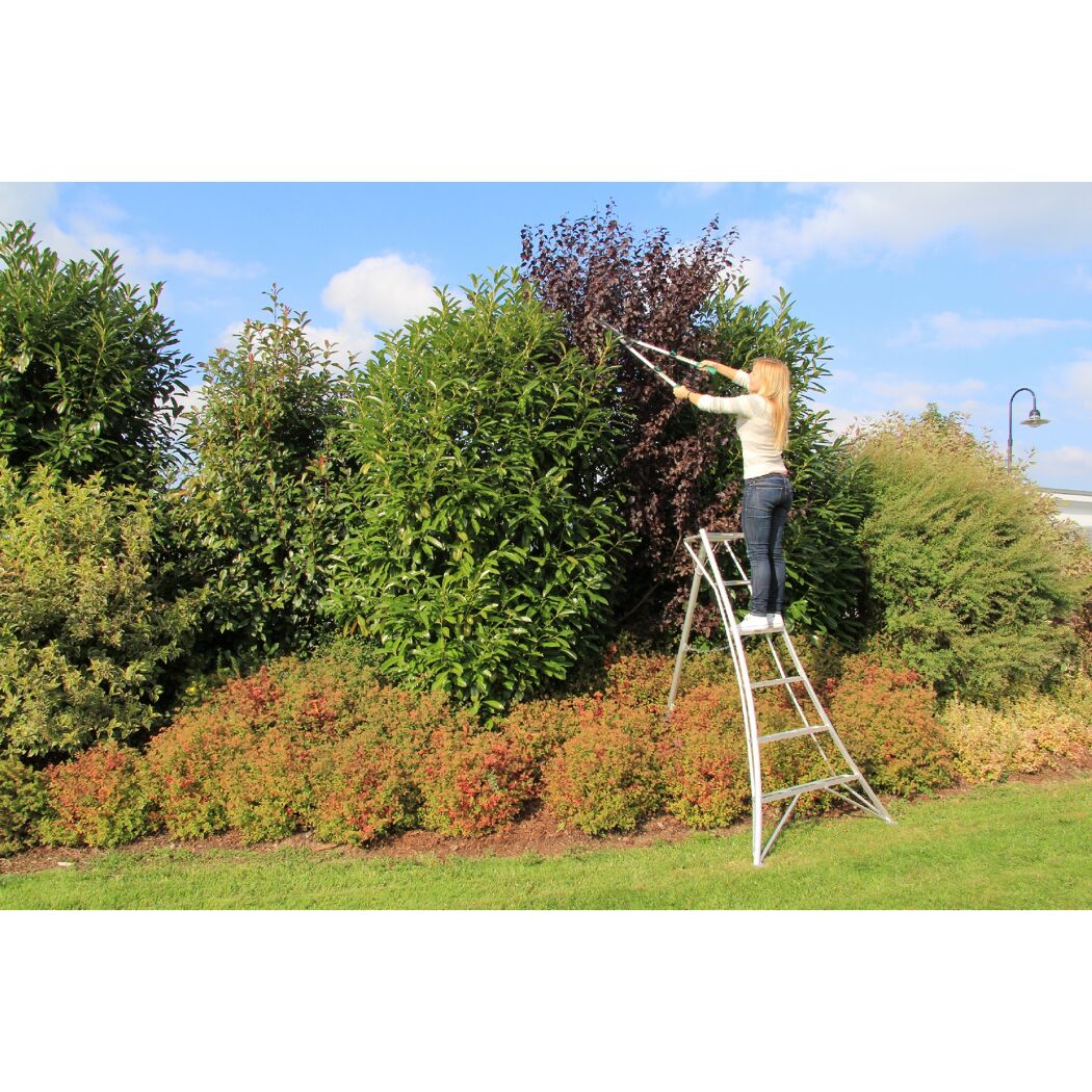 Person schneidet Hecke mit Gartenschere