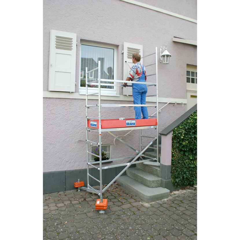 Person auf einem Gerüst vor einem Haus