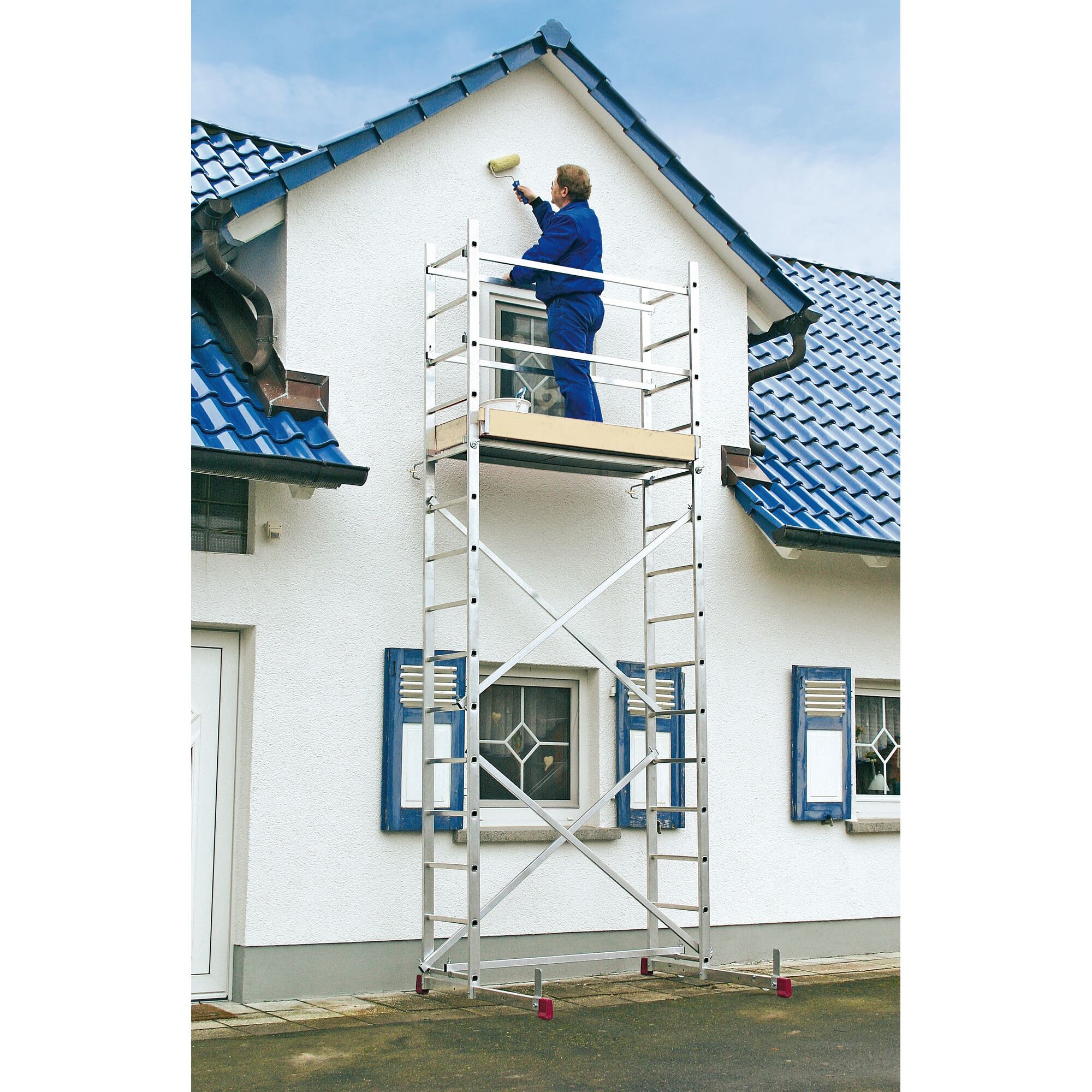 Person streicht Hauswand mit Farbrolle von Gerüst aus.