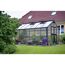 Gewächshaus im Garten mit Sitzmöbeln davor
