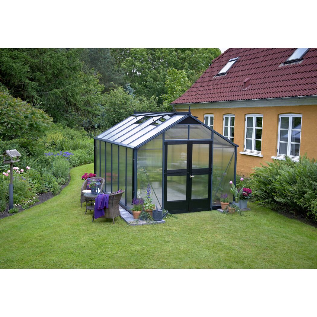 Gewächshaus im Garten neben einem Haus