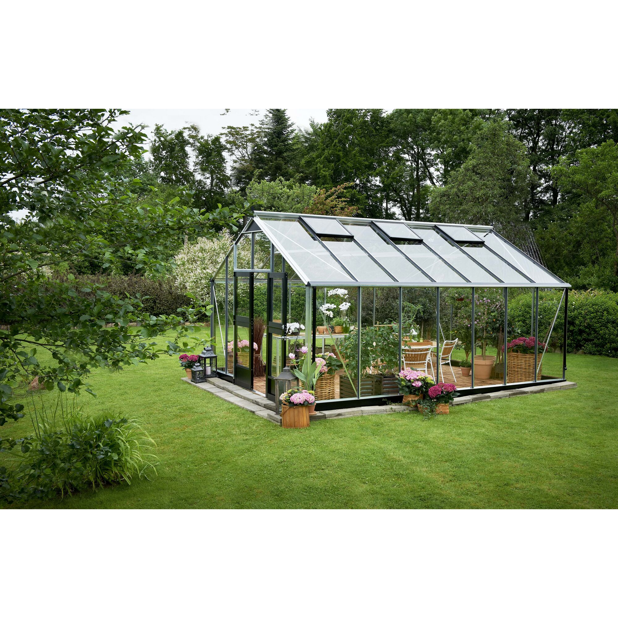 Gewächshaus mit geöffneten Dachfenstern und Möbeln im Garten.