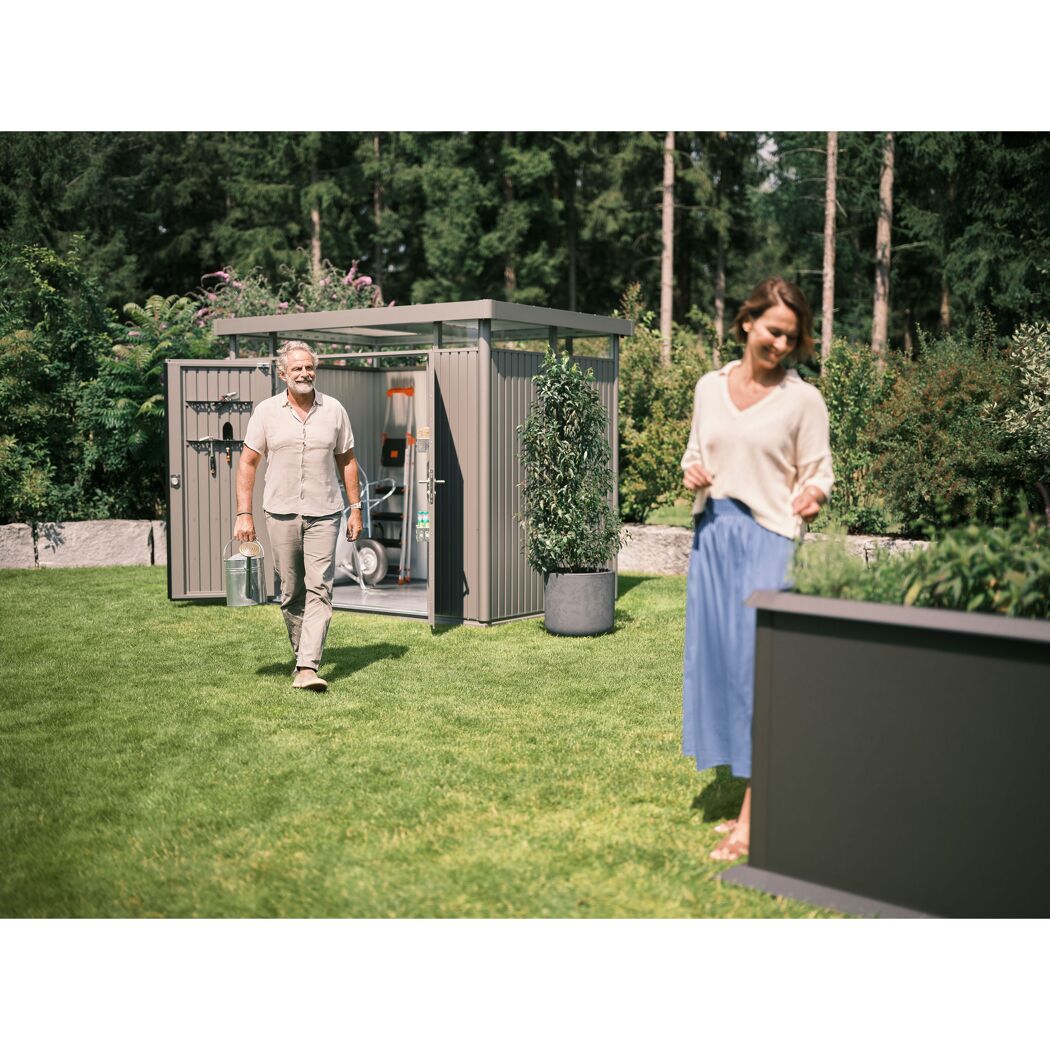 Person verlässt Gerätehaus 'HighLine 2' mit Gießkanne im Garten.