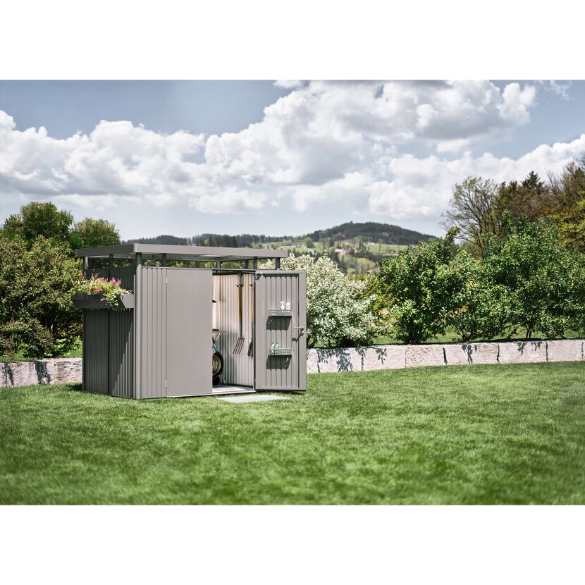 Gerätehaus 'HighLine 2' im Garten mit Mistgabel und Schaufel.