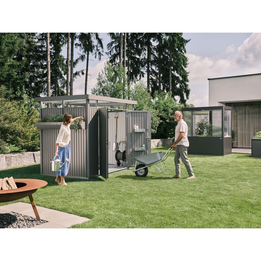 Gartenhaus 'HighLine 2' mit Gießkanne und Schubkarre im Einsatz.
