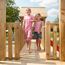 Zwei Kinder gehen barfuß über eine Holzbrücke.