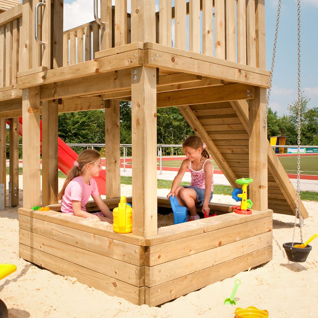 Zwei Kinder spielen im Sandkasten eines Spielturms.