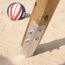 Holzbalken mit Metallfuß im Sand, daneben ein Basketball.