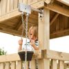 Kind mit Sandeimer und Kette an Spielhaus
