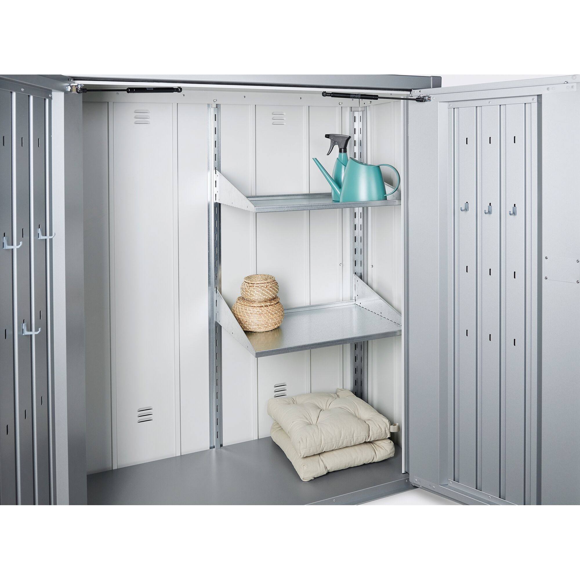 Offener Geräteschrank mit Regalen, Gießkanne und Kissen