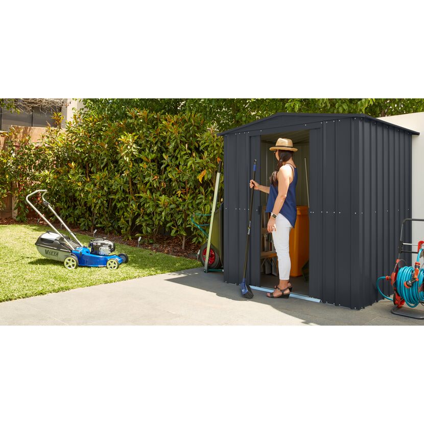 Person stellt Besen in Gartenhaus Gartenmanager Dream