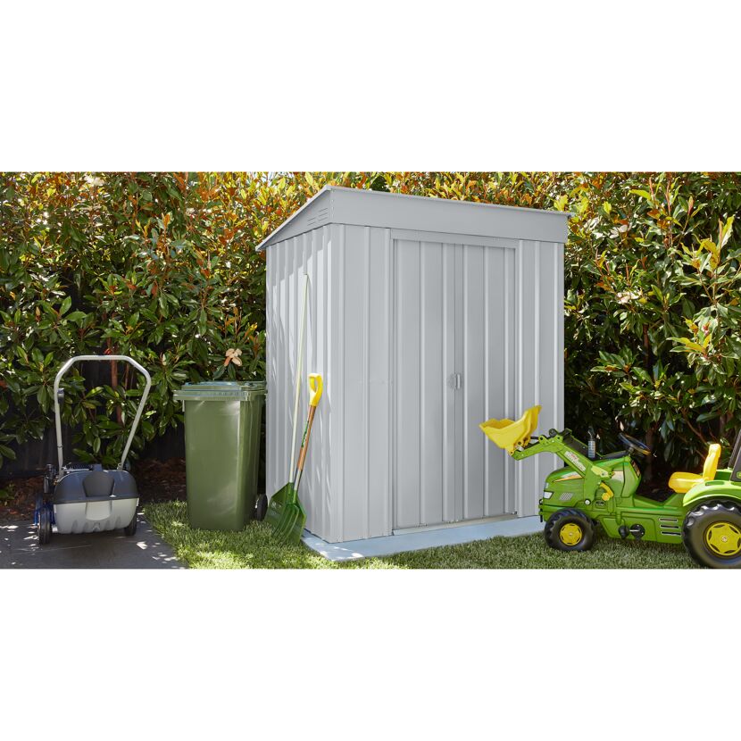 Metallgerätehaus im Garten, daneben ein Rasenmäher, eine Mülltonne und ein Spielzeugtraktor