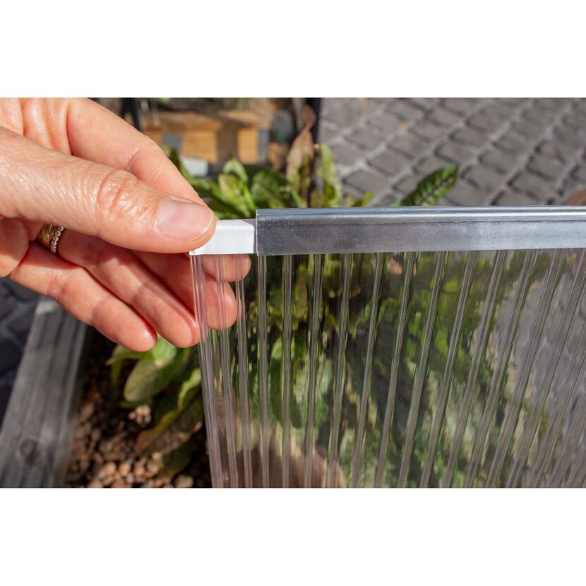 Person hält ein transparentes Gewächshauspaneel in der Hand.