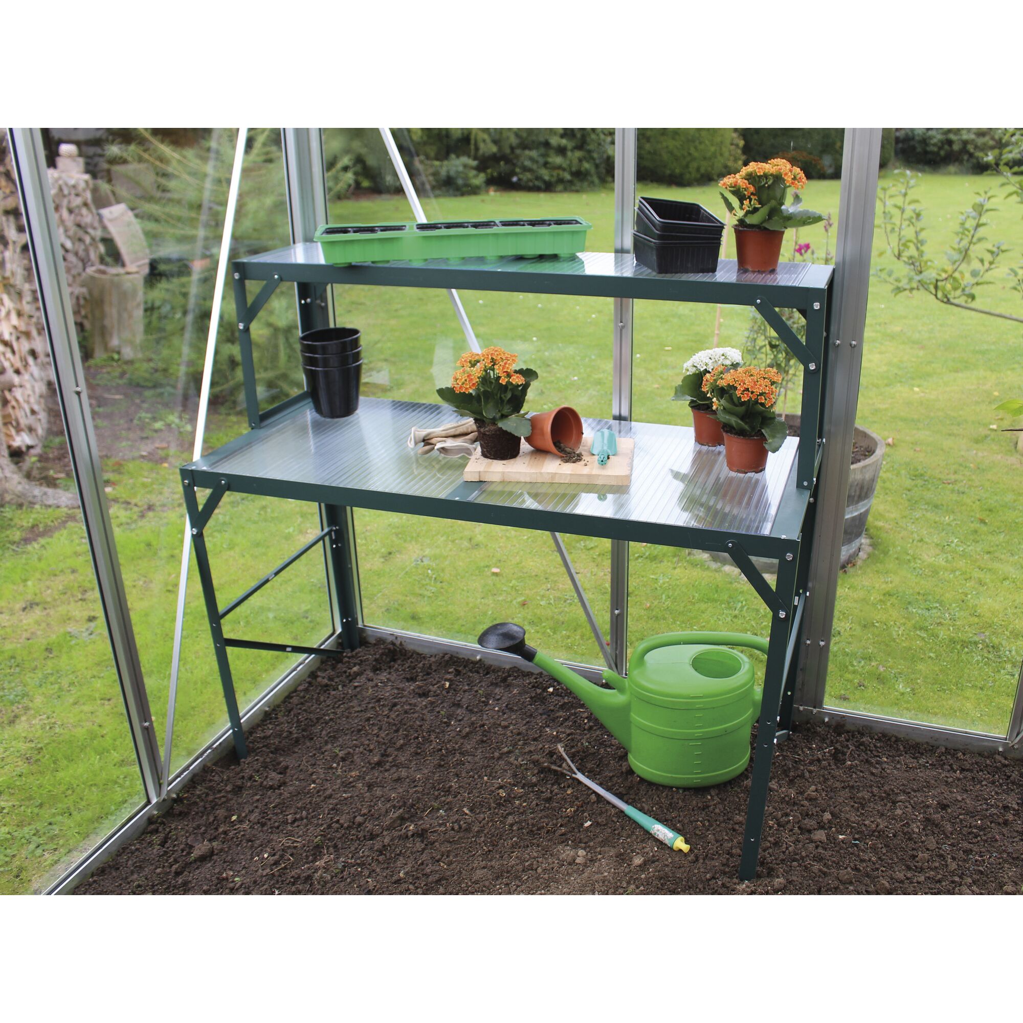 Gewächshausregal mit Blumen und Gießkanne