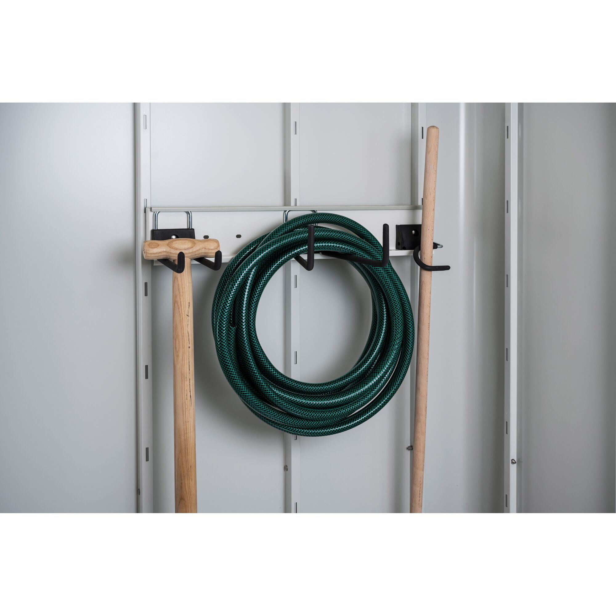 Gartenschlauch, Spaten und Besen an Haken