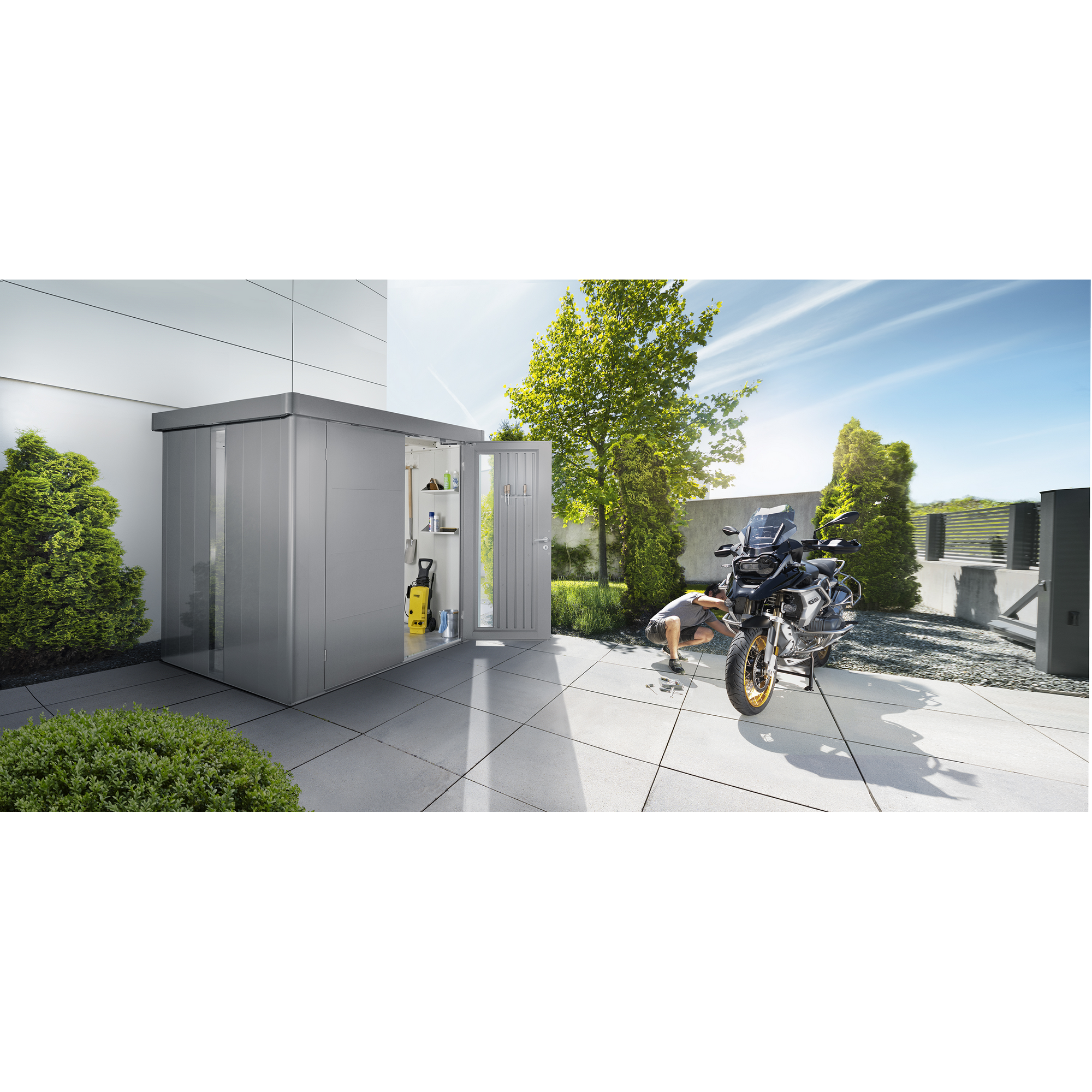 Person repariert Motorrad vor Gerätehaus