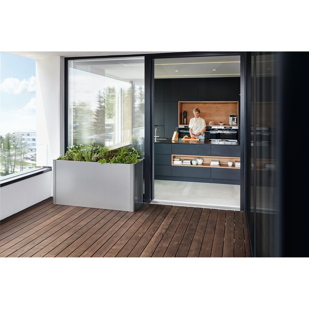 Person beim Kochen in einer modernen Küche mit Balkon-Blumenkasten