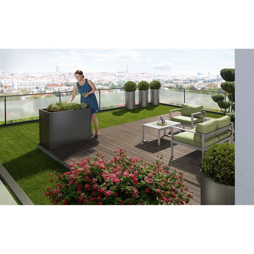 Person pflegt Kräuter im Hochbeet auf Dachterrasse