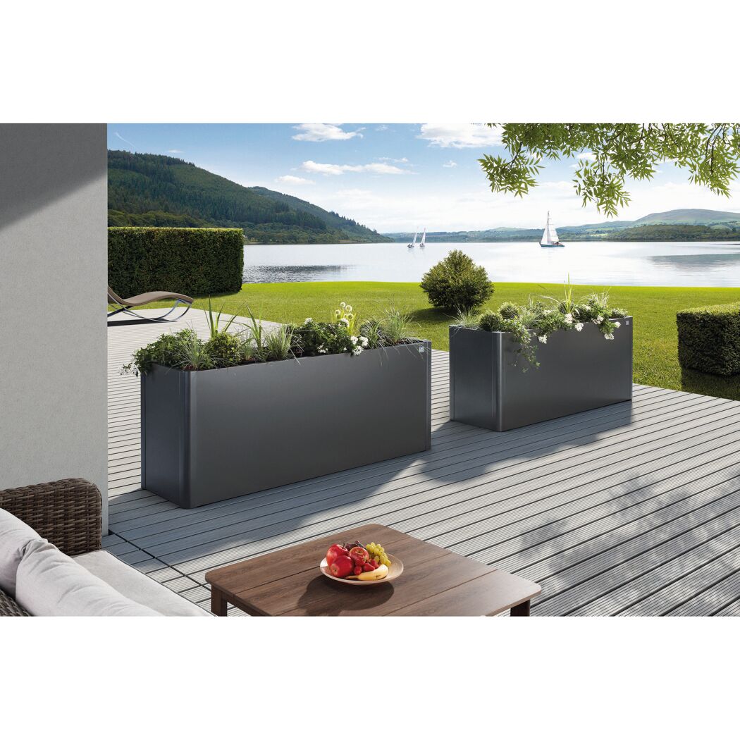 Zwei graue Pflanzkästen auf einer Terrasse am See